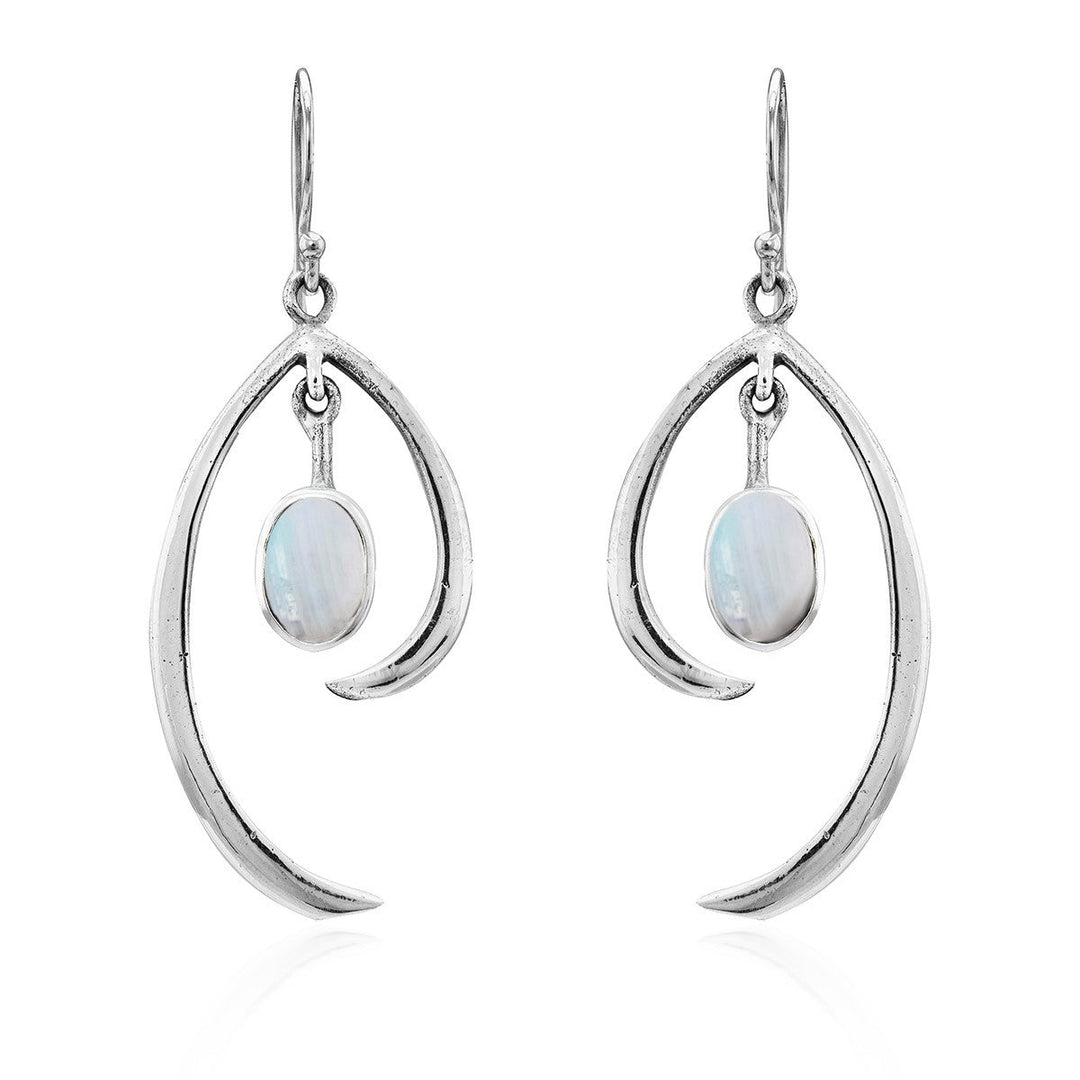 The Primrose Earrings in various gemstones by Gallardo & Blaine Designs are a pair of elegant sterling silver hook earrings with a teardrop shape, each featuring an oval moonstone at the center. The polished silver design elegantly curves around the shimmering stone, exuding minimalist elegance and creating a modern, sophisticated look.