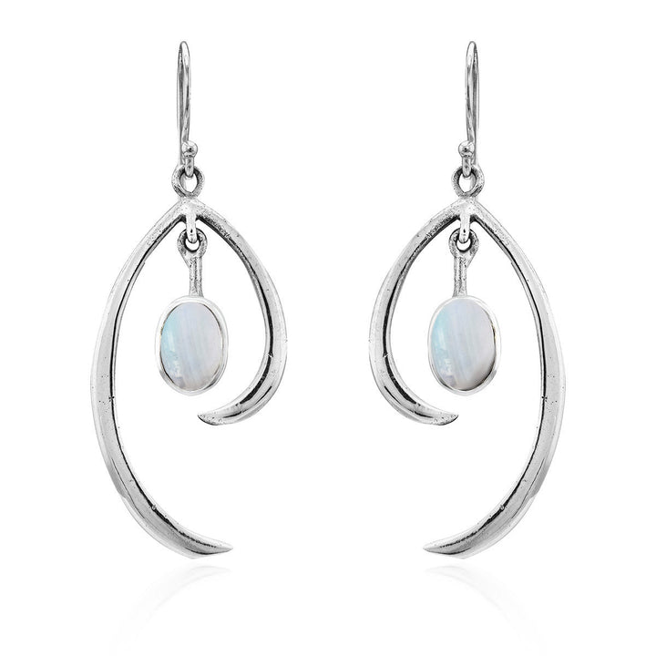 The Primrose Earrings in various gemstones by Gallardo & Blaine Designs are a pair of elegant sterling silver hook earrings with a teardrop shape, each featuring an oval moonstone at the center. The polished silver design elegantly curves around the shimmering stone, exuding minimalist elegance and creating a modern, sophisticated look.