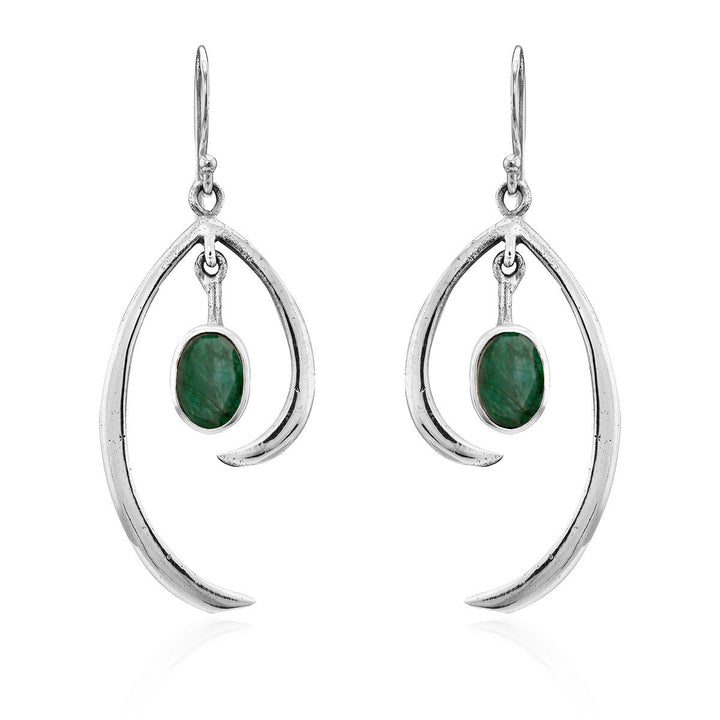 Discover the Primrose Earrings in various gemstones by Gallardo & Blaine Designs, a pair of sterling silver earrings that exude minimalist elegance. These silver drop earrings feature an abstract curved design with an oval green stone hanging in the center, all suspended from simple hooks.