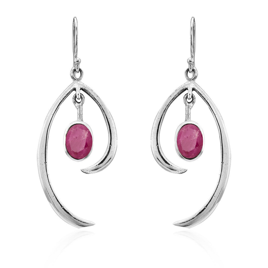 The Gallardo & Blaine Designs Primrose Earrings in various gemstones are a pair of sterling silver drop earrings featuring an elegant, curved design. Each earring showcases an oval-shaped pink gemstone hanging in the center. The minimalist elegance of the simple hooks adds to the delicate and refined aesthetic of this jewelry.