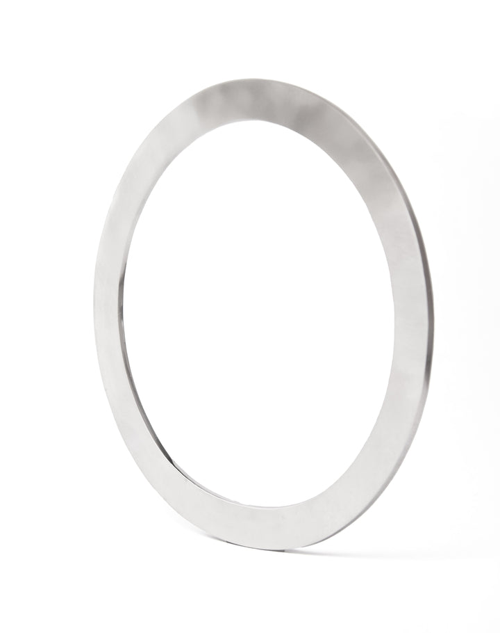 A close-up of a thin, sterling silver Satin Bangle by Gallardo & Blaine Designs standing upright against a white background. The ring has a smooth, reflective surface. The angle of the image shows the ring slightly tilted to the left, highlighting its bangle-like elegance.