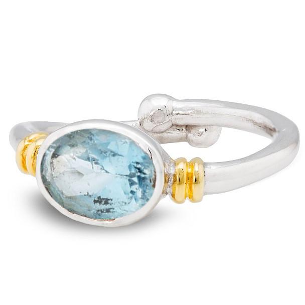 A Gallardo & Blaine Designs Senna Ring in various gemstones featuring an oval-shaped, blue gemstone as the centerpiece. The band has gold accents near the setting, adding contrast and elegance to the design. The adjustable ring has a stylish, modern look with a slightly open band on one side.