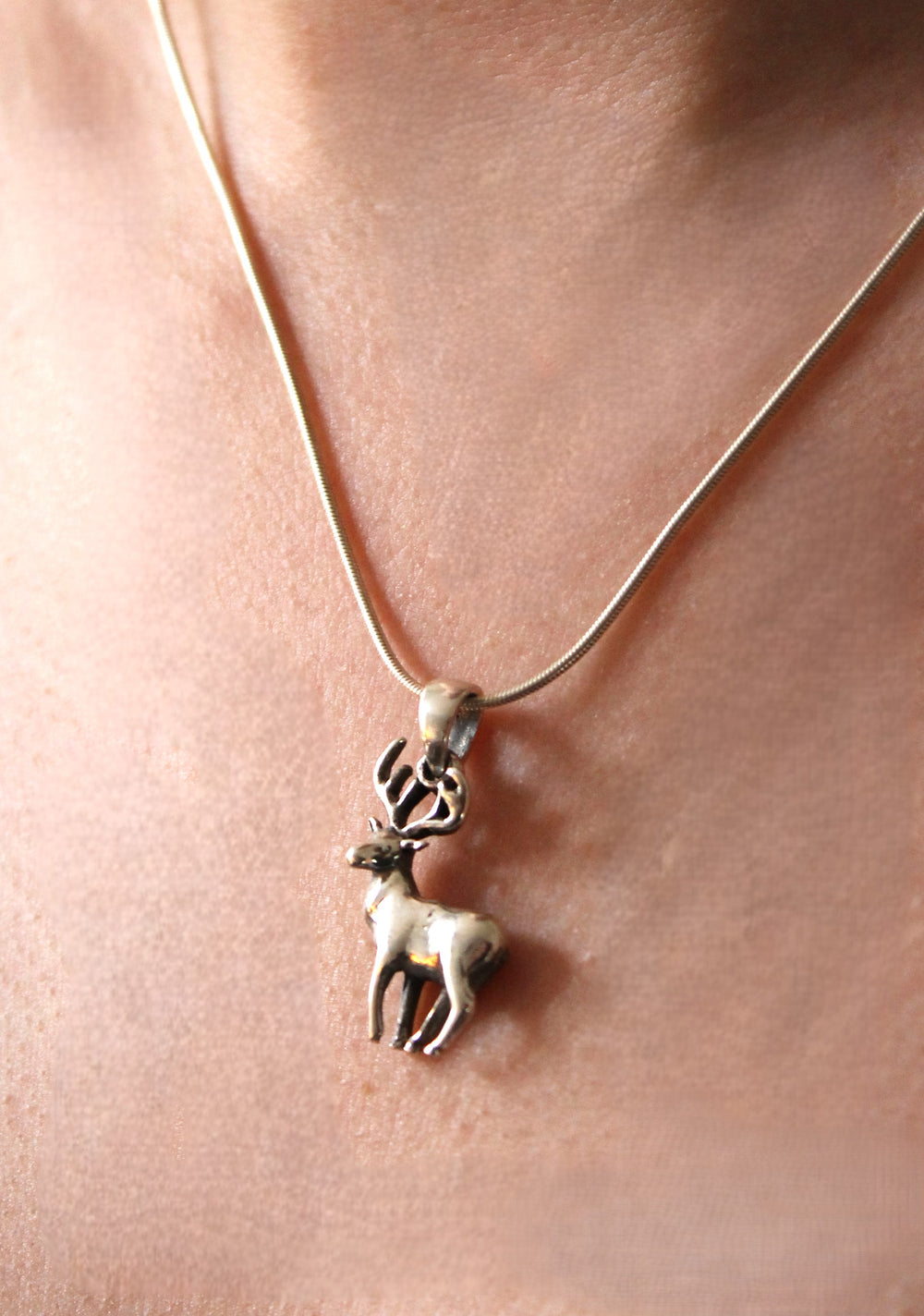 The Gallardo & Blaine Designs Wildlife Pendant - Stag With Chain is a silver necklace featuring an antlered deer pendant—a striking, nature-inspired accessory worn elegantly against the skin.
