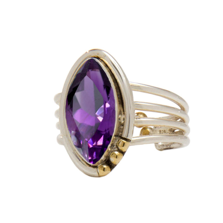 A gold Tulip Ring in various gemstones by Gallardo & Blaine Designs featuring a large, marquise-cut purple gemstone as its centerpiece. The band splits into four parallel strands, connecting to the stone with small gold accents on one side, adding an intricate and elegant touch to this Art Deco adjustable ring design.