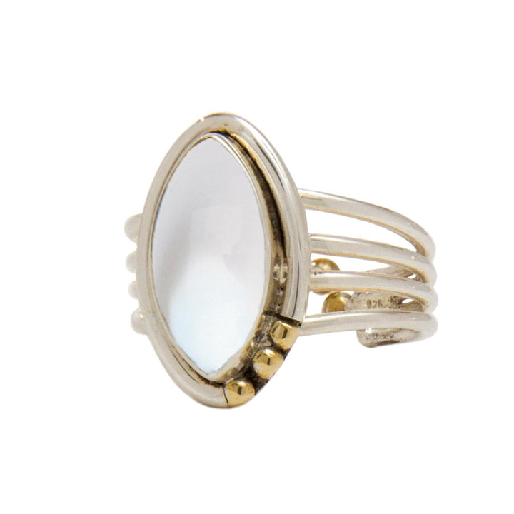 A silver Tulip Ring in various gemstones by Gallardo & Blaine Designs featuring an elongated oval-shaped, facet-cut white gemstone. The band splits into three distinct strands on each side of the stone, and small gold accents are positioned on one side of the setting.