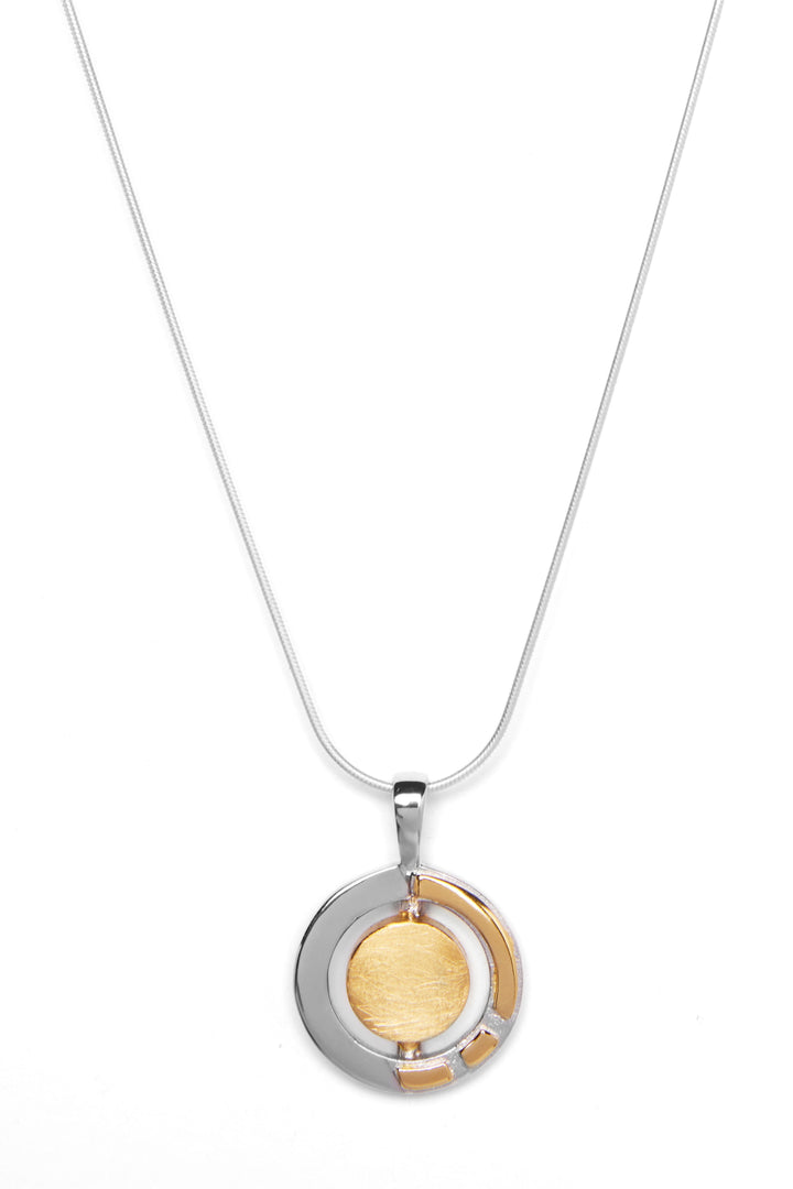 A silver necklace featuring a round, dual-tone Urú Small Pendant & Chain by Gallardo & Blaine Designs. The pendant has concentric circles, with an inner gold-colored circle surrounded by a partial silver ring. The thin, elegant sterling silver chain complements the design beautifully against the white background.