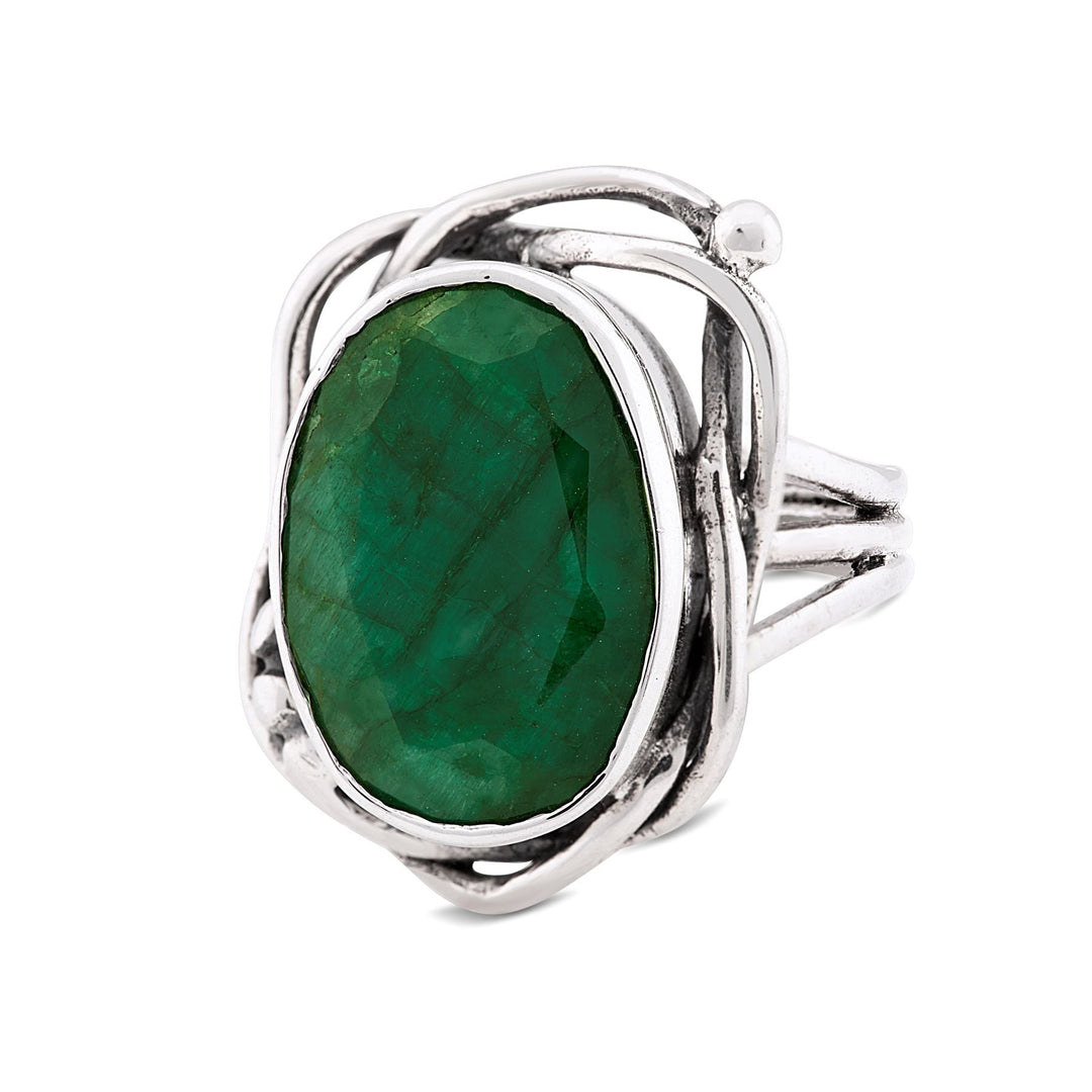 A captivating Gallardo & Blaine Designs Whirlpool Ring in various gemstones with an ornate band design features an oval-shaped, faceted green gemstone at its center. The gemstone is set in an intricate, looping silver setting that adds detail and elegance to the piece.