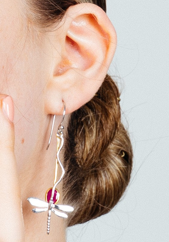 Close-up of a woman's ear adorned with a Willow Earring in Various Gemstones by Gallardo & Blaine Designs. Her hair is tied back in a bun, and she lightly touches her cheek with her fingers. The background is neutral, allowing the intricate detailing of the earring to stand out beautifully.