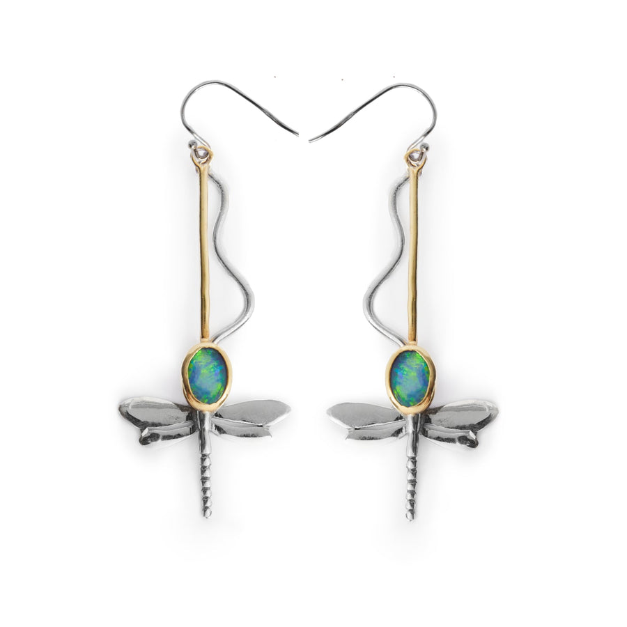 The Willow Earrings in Various Gemstones by Gallardo & Blaine Designs are a pair of dangle earrings shaped like dragonflies, crafted from silver and gold. Each earring features a blue-green oval gemstone as the dragonfly's thorax, with delicate wings and a slender, tapered body extending downward. The silver-toned hooks add a simple yet elegant touch.