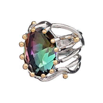 The Willow Ring in various gemstones is a silver piece with a large, oval-shaped, multicolored gemstone at its center. Reflecting hues of green, purple, and blue, this chunky statement gemstone ring from Gallardo & Blaine Designs also features an intricate claw-like band design with small gold accents around the adjustable setting.