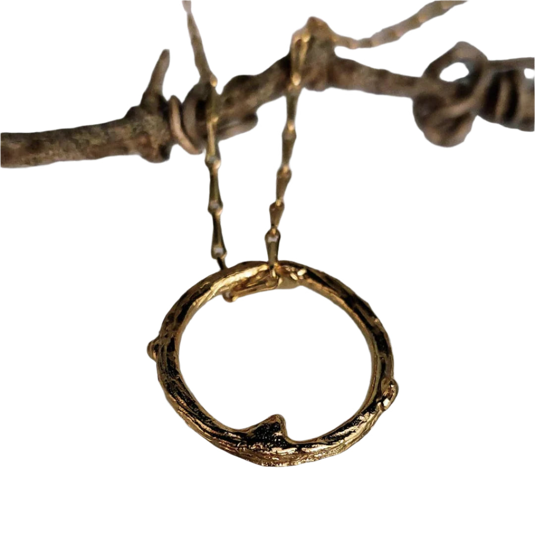 The Faerie Thorn Pendant Gold Plated by Caroline Stokesberry-Lee features a textured, rustic design in 18ct gold-plated sterling silver, elegantly suspended from a delicate chain draped over barbed wire.