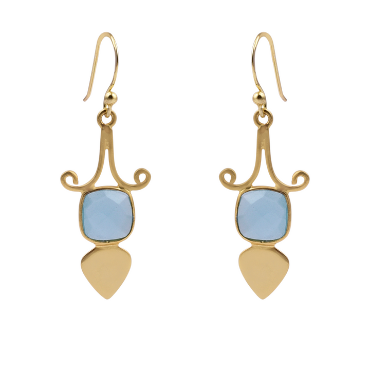 A pair of Gold Shield Aqua Chalcedony Earrings by Watermelon Tropical featuring a blue, square-cut aqua chalcedony gemstone set in an intricate gold design with swirling accents. Below the gemstone, a gold teardrop-shaped piece completes each piece of handmade jewelry.