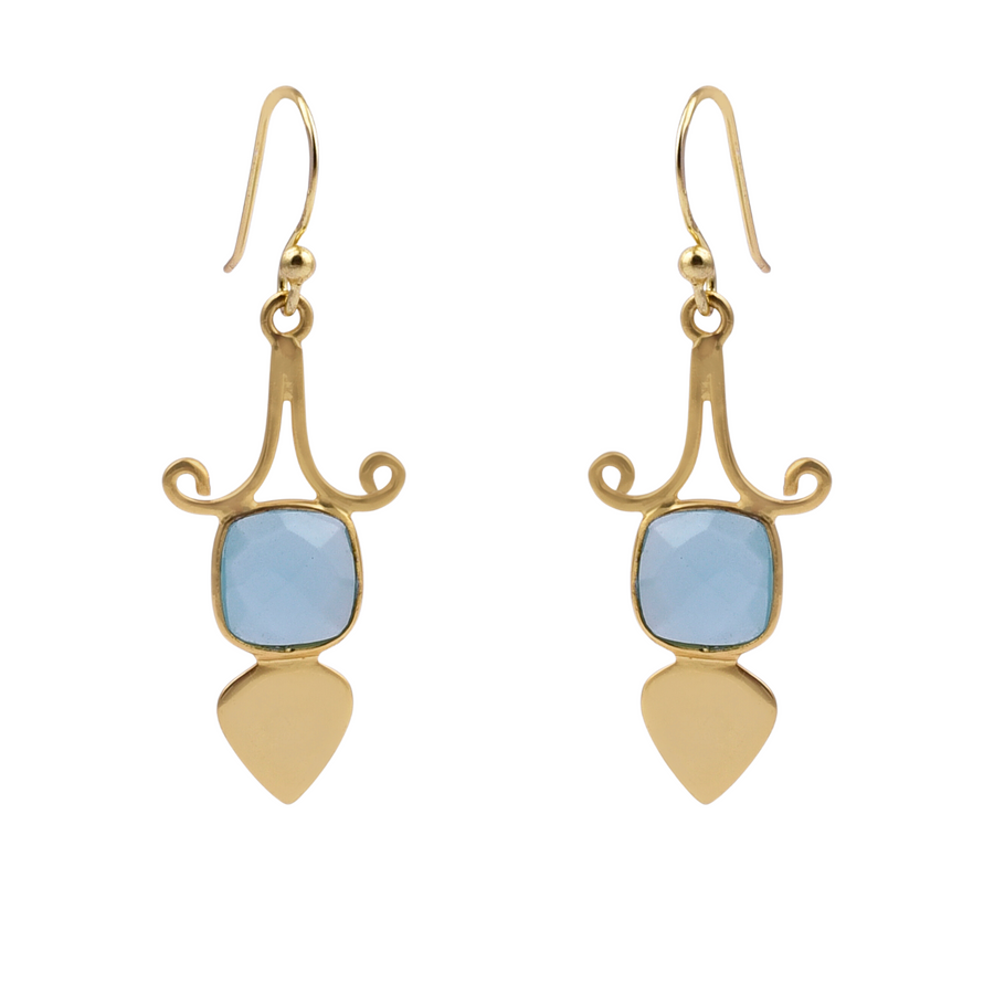 A pair of Gold Shield Aqua Chalcedony Earrings by Watermelon Tropical featuring a blue, square-cut aqua chalcedony gemstone set in an intricate gold design with swirling accents. Below the gemstone, a gold teardrop-shaped piece completes each piece of handmade jewelry.