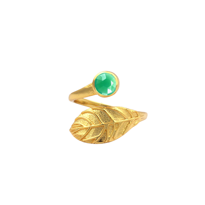 A **Hannah Gold Ring in Chrysoprase** by **Watermelon tropical** wraps around the finger. One end of the ring is designed as an intricate, detailed leaf, while the other end features a green, faceted Chrysoprase gemstone.