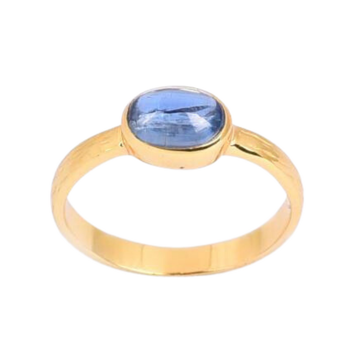 A gold plated sterling silver Kyanite Gold Ring by Watermelon Tropical with a blue oval-shaped gemstone set in a bezel setting. The band is smooth and polished, highlighting the vivid blue color of the gemstone. The ring has a simple yet elegant design, perfect for any occasion.