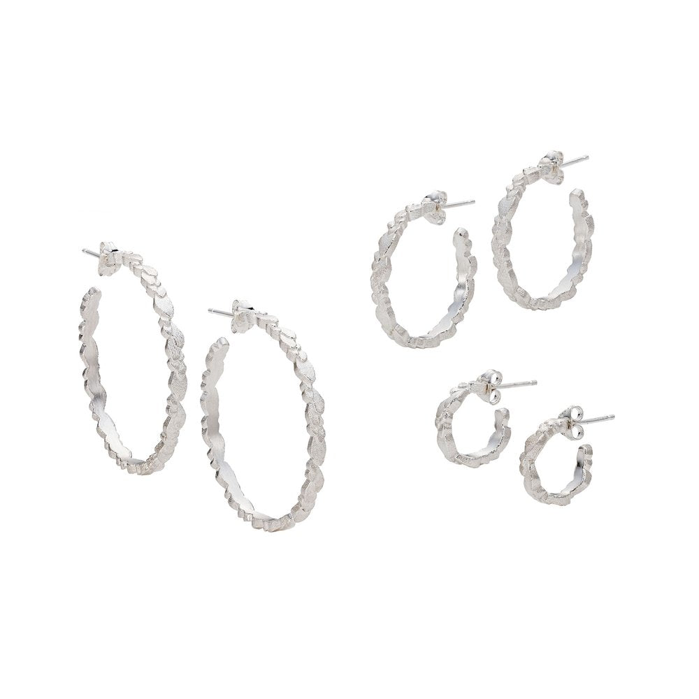 A set of three pairs of Leoma Drew Freeform Layered Wing Hoop Earrings in Frosted Silver, each with a textured surface. The set includes large, medium, and small hoop sizes in Freeform Layered Wing designs, displayed against a white background. The earrings are designed with post and butterfly back closures.