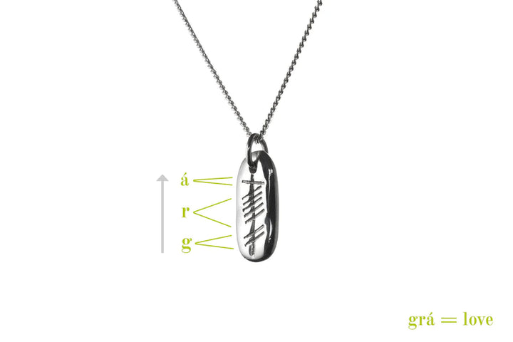 An Ogham Treasure Love (Grá) Carved Silver Pendant with an Ogham Love pendant, featuring the Gaelic word for love, "grá." The ancient Celtic script is beautifully annotated on the pendant, while the translation "grá = love" is elegantly displayed in green text in the bottom right corner.