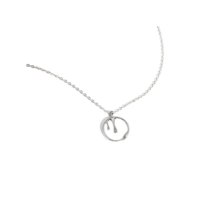 A Melting Pendant Necklace Silver by Marie June Jewellery features a delicate chain and a round pendant with a stylized letter "m" inside the circle. The background is plain white.