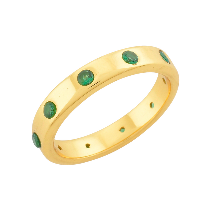 The Shyla Mela Ring boasts a sterling silver band adorned with small, round green gemstones evenly spaced along its length. With a smooth, polished finish and slightly inset stones, this piece exudes timeless elegance.