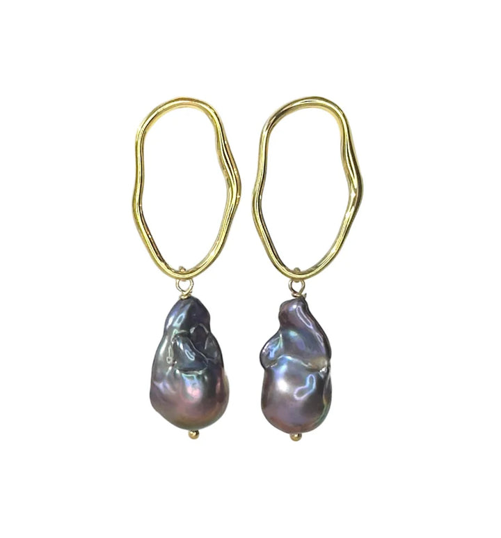 The Millie Earrings by Aria V feature irregular oval gold electroplated brass hoops, each accented with a uniquely shaped iridescent baroque pearl. Available in various colours.