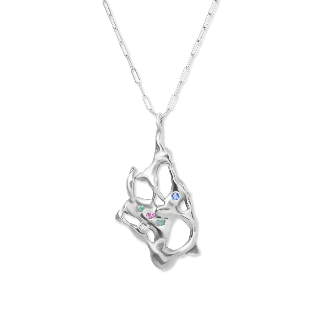 The Molten Necklace with Gemstones by Madeleine Sculptural Jewellery features an abstract, organic-shaped silver pendant with open spaces, set with pink, green, and blue gems, and hangs from a delicate chain for a unique, handmade look.