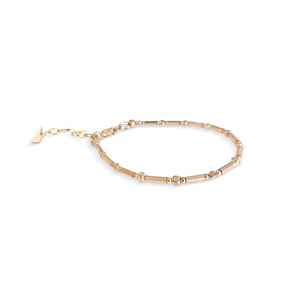 gold thin bracelet featuring tube and crimp style round beads.
