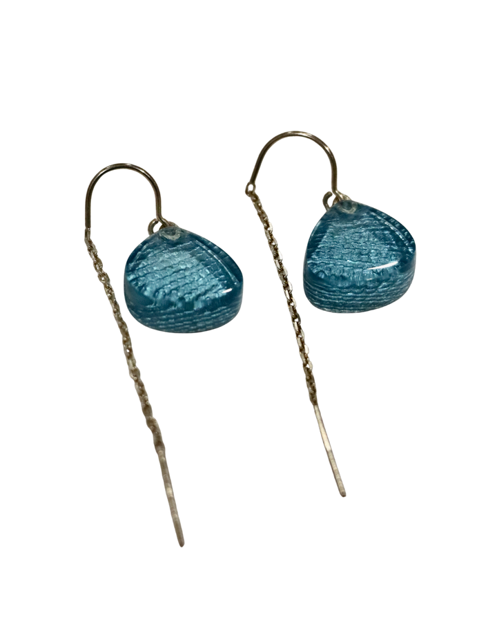 The MX.design Acrylic Aquamarine Earrings with Chain Back Silver feature translucent blue teardrop beads and elegant chain-like dangles, offering a sleek, modern accent to your style.