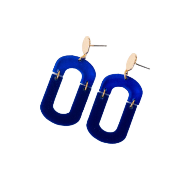 A pair of handmade earrings featuring large, geometric, hollow rectangle shapes in deep blue, attached to small gold-plated brass oval studs. The Navy & Cobalt Blue Acrylic Fire Earrings by Studio Nok Nok have a modern design with a minimalist aesthetic.