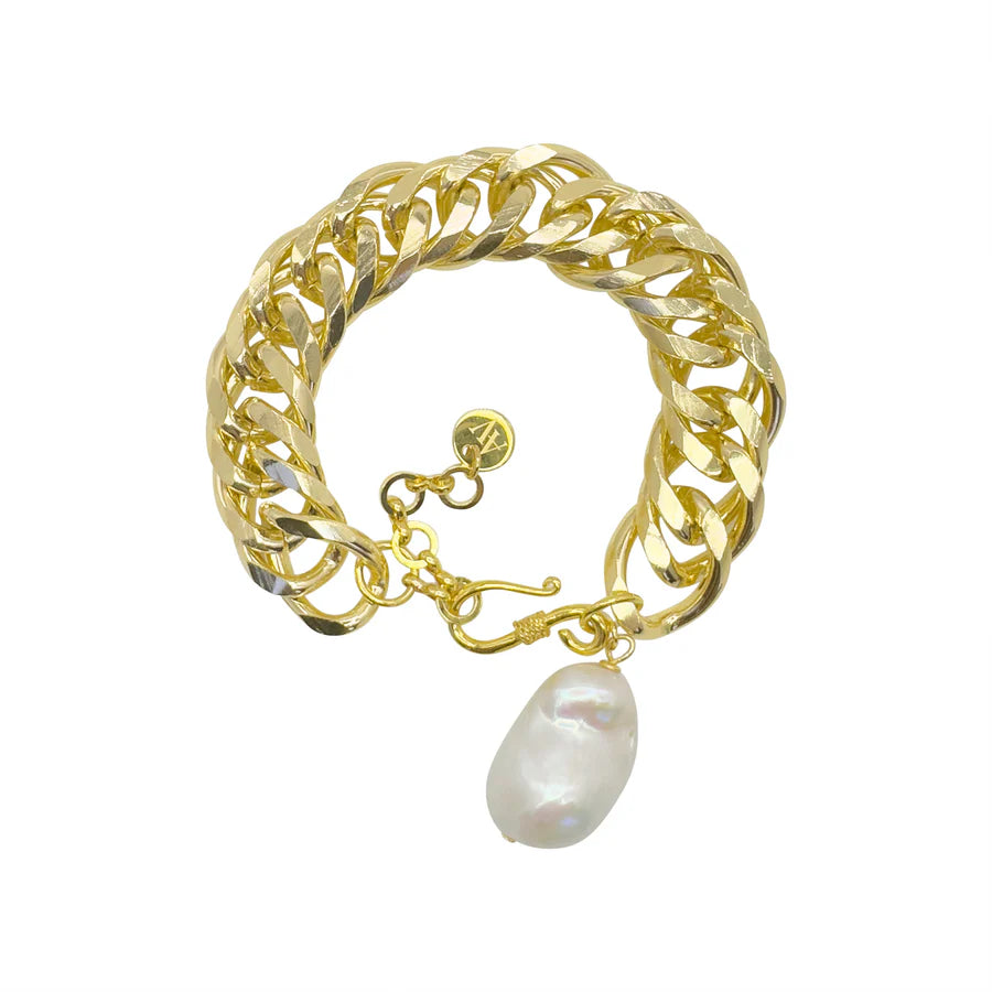 The Pearl Drop Bracelet by Aria V is a chunky gold-plated piece with a large white baroque pearl charm and a small round gold tag, handmade in Dublin and shown on a white background.
