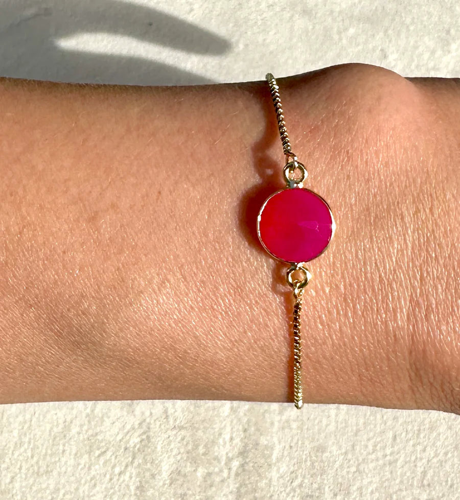 The Pink Chalcedony Single Drop Bracelet by Aria V is a gold-plated, handmade piece crafted in Dublin, featuring a round, vibrant pink chalcedony gemstone centerpiece and shown worn on the wrist against a light background.