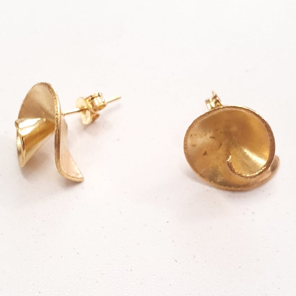 A pair of **Small Swirl Earrings** by **Georgia Charal** with an abstract, folded design are displayed against a plain white background. These gold-plated earrings have a shiny, metallic finish and are laid out to show their front and side views.