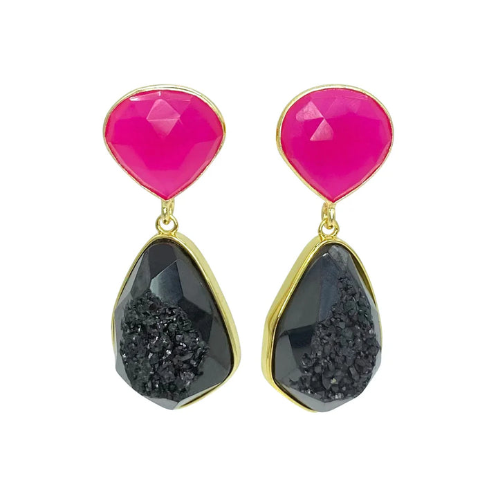 A pair of Aria V Poppy Earrings featuring bright pink faceted stones at the top and irregularly shaped black druze agate stones with a rough, textured surface at the bottom. The stones are set in a shiny gold-tone metal.