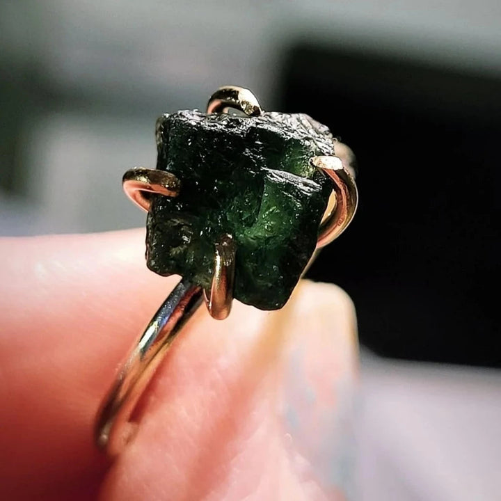 The Caroline Stokesberry-lee Raw Green Apatite Gold Filled Ring features a raw green apatite gemstone held by four prongs, shown in close-up with a blurred background.