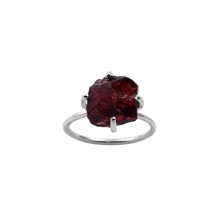 The Rough Garnet Silver Claw Ring by Watermelon Tropical features a large, rough-cut garnet held by four prongs. The stone's natural, unpolished appearance adds a raw, organic element to the sleek, minimalist band. This piece of handmade jewellery boasts an overall design that is both elegant and rustic.