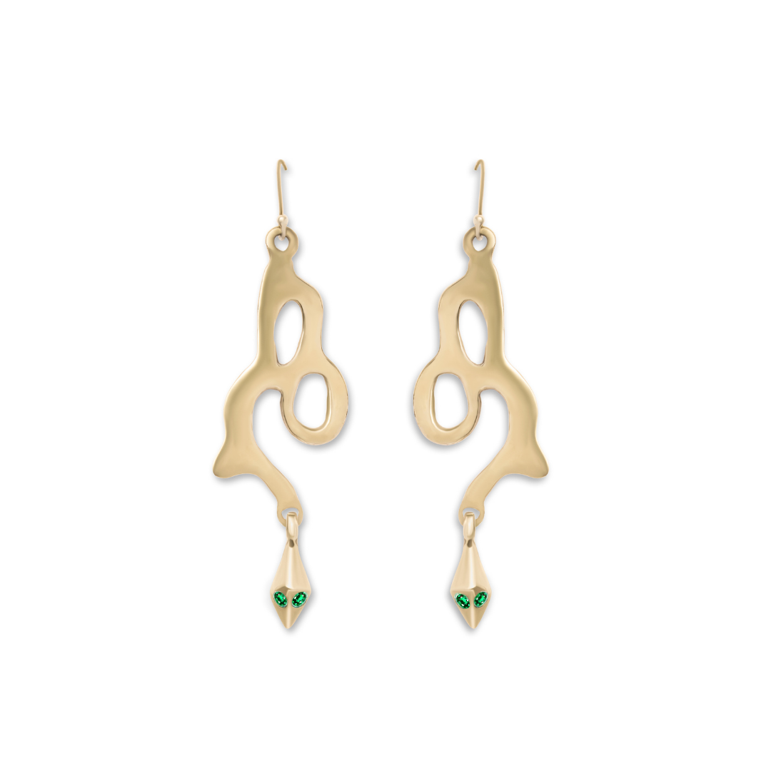 The Serpent Earrings by Madeleine Sculptural Jewellery feature gold, abstract dangles in fluid shapes, each with two green gemstone “eyes,” expertly crafted from recycled brass for a touch of sustainable elegance.