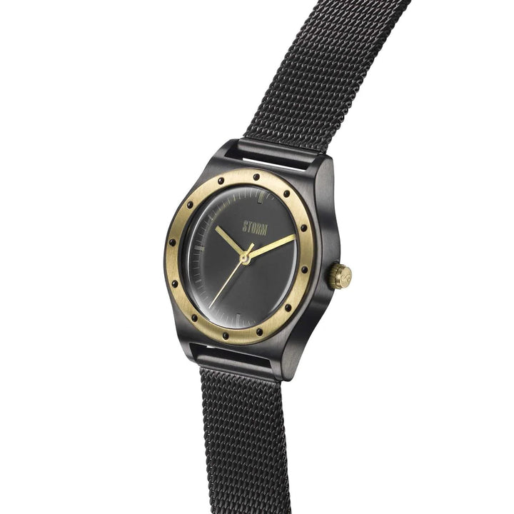 A Storm Sian Slate wristwatch with a black mesh strap and a black face. The watch features a gold bezel with small black dots and a gold crown. Its minimalist design includes slim hour and minute hands, crafted from sustainable materials, and a subtle Storm Watches logo at the 12 o’clock position.