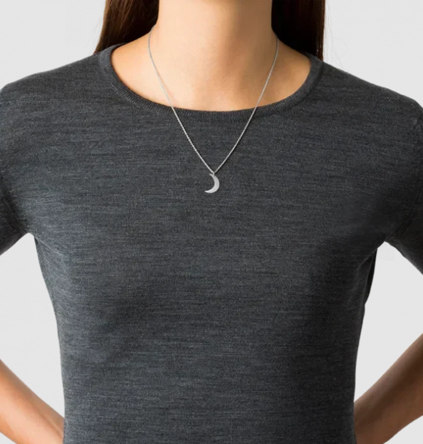 A close-up of a woman wearing a dark gray crewneck t-shirt and a silver crescent moon pendant necklace.