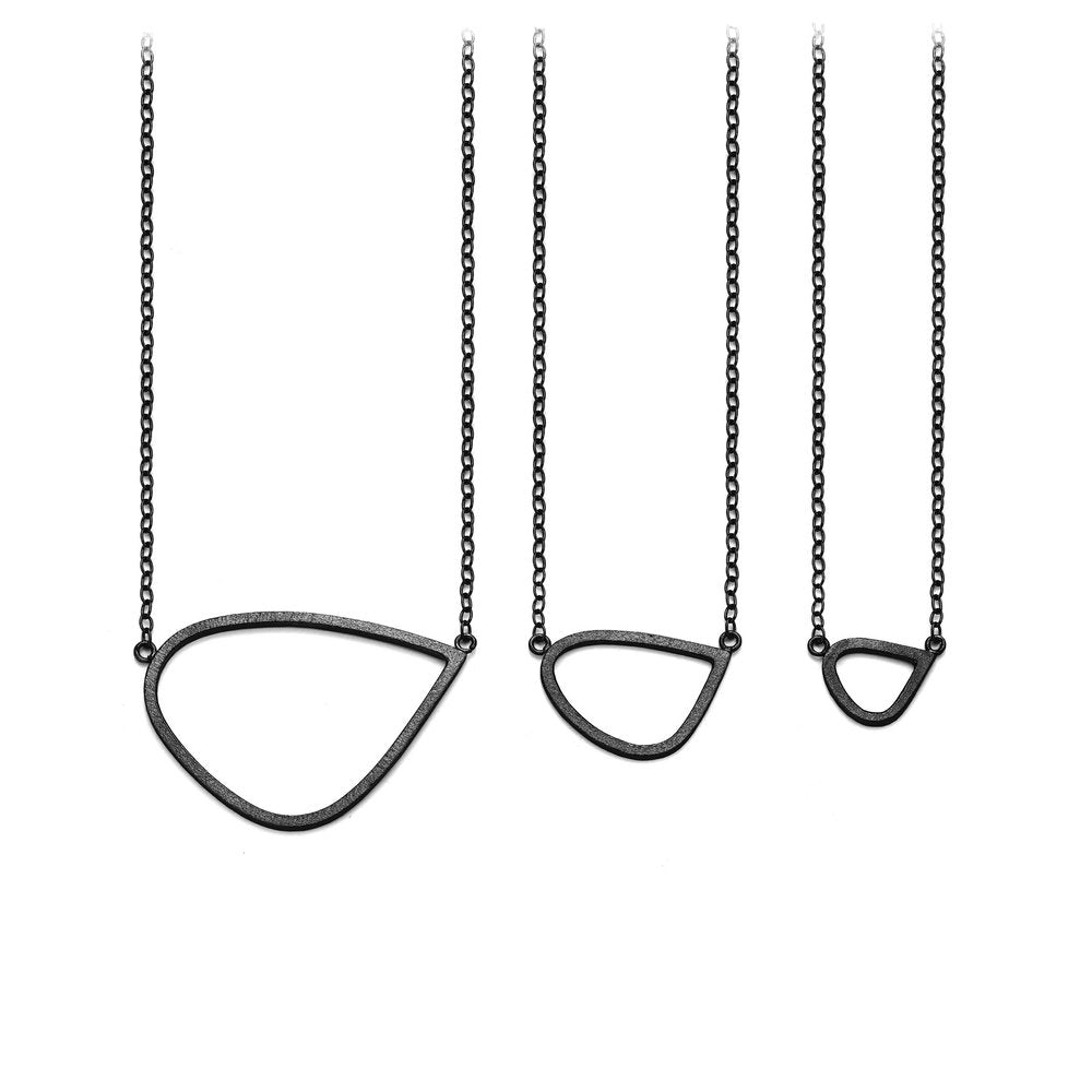 Three Oxidised Silver Single Wing Pendants by Leoma Drew, featuring handcrafted open teardrop shapes in three sizes, hang on delicate chains. The minimalist design against a plain white background highlights their subtle elegance.