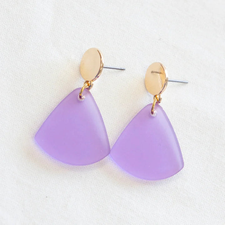 A pair of stylish, gold-plated Smile 07 Earrings with circular studs attached to translucent, triangular purple pendants made from upcycled wood by Studio Nok Nok, set against a white background.