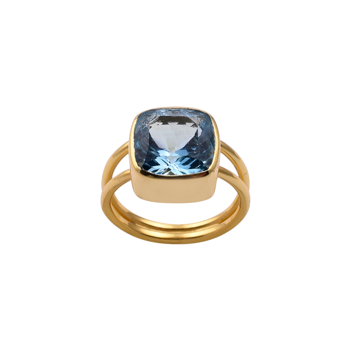 Introducing the Watermelon Tropical Square Blue Quartz Gold Ring: A gold vermeil ring featuring a large, square-cut Blue Quartz set in a bezel setting. The handmade jewellery piece has a double band design, giving it a modern and elegant appearance. The gemstone catches the light, showcasing its facets and depth.