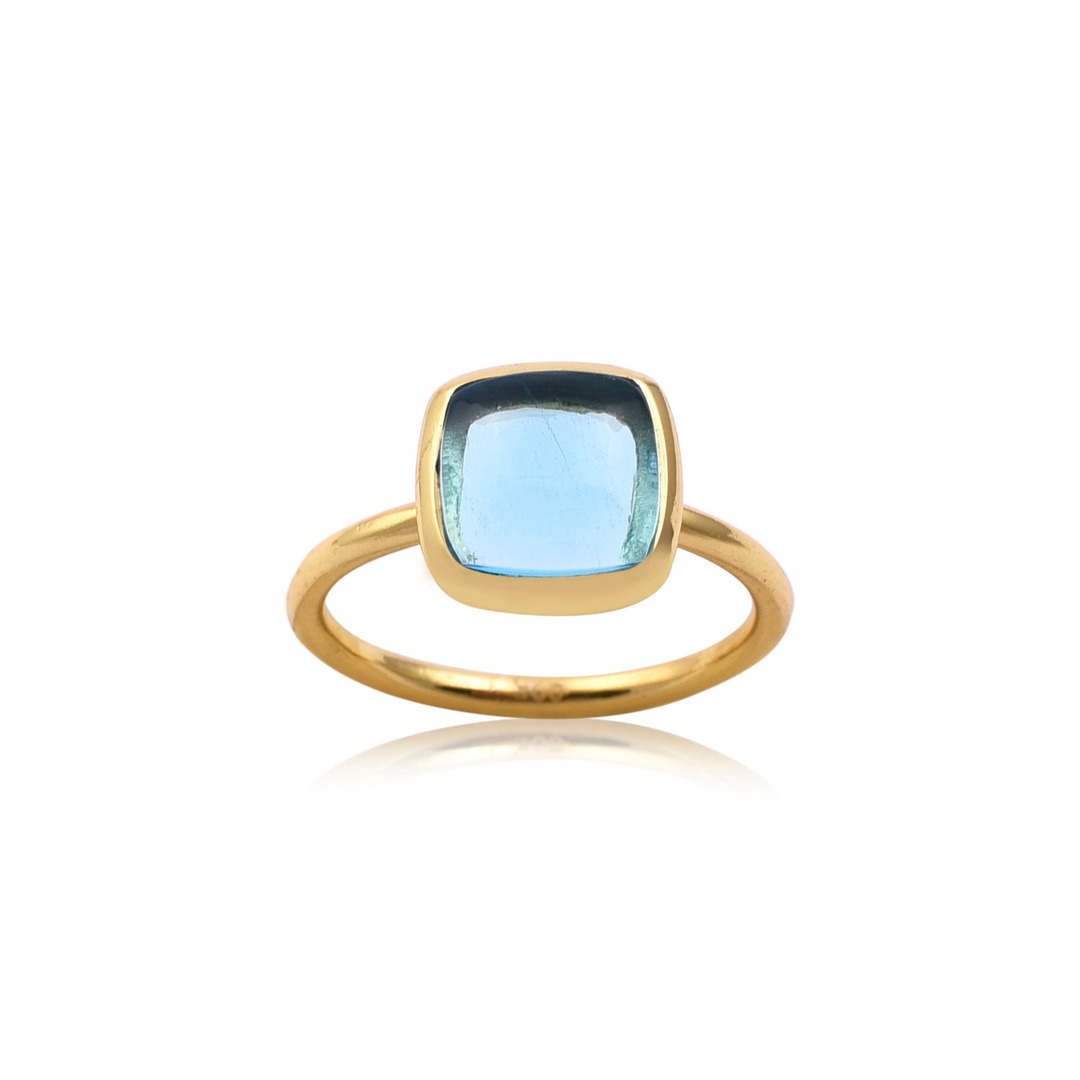 A gold vermeil ring featuring a large, rectangular cushion-cut aquamarine gemstone set in a simple bezel setting. The light blue gemstone adds an elegant touch to the minimalist, handmade jewellery design. The ring is photographed against a white background.

The Square Blue Topaz Gold Ring by Watermelon Tropical adds a touch of elegance with its rectangular cushion-cut aquamarine gemstone set in gold vermeil.