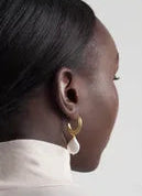 A close-up side view of a woman with dark skin and straight, pulled-back hair, wearing a white collared shirt and Inner Island's Strata Thin Earrings with Pearl.
