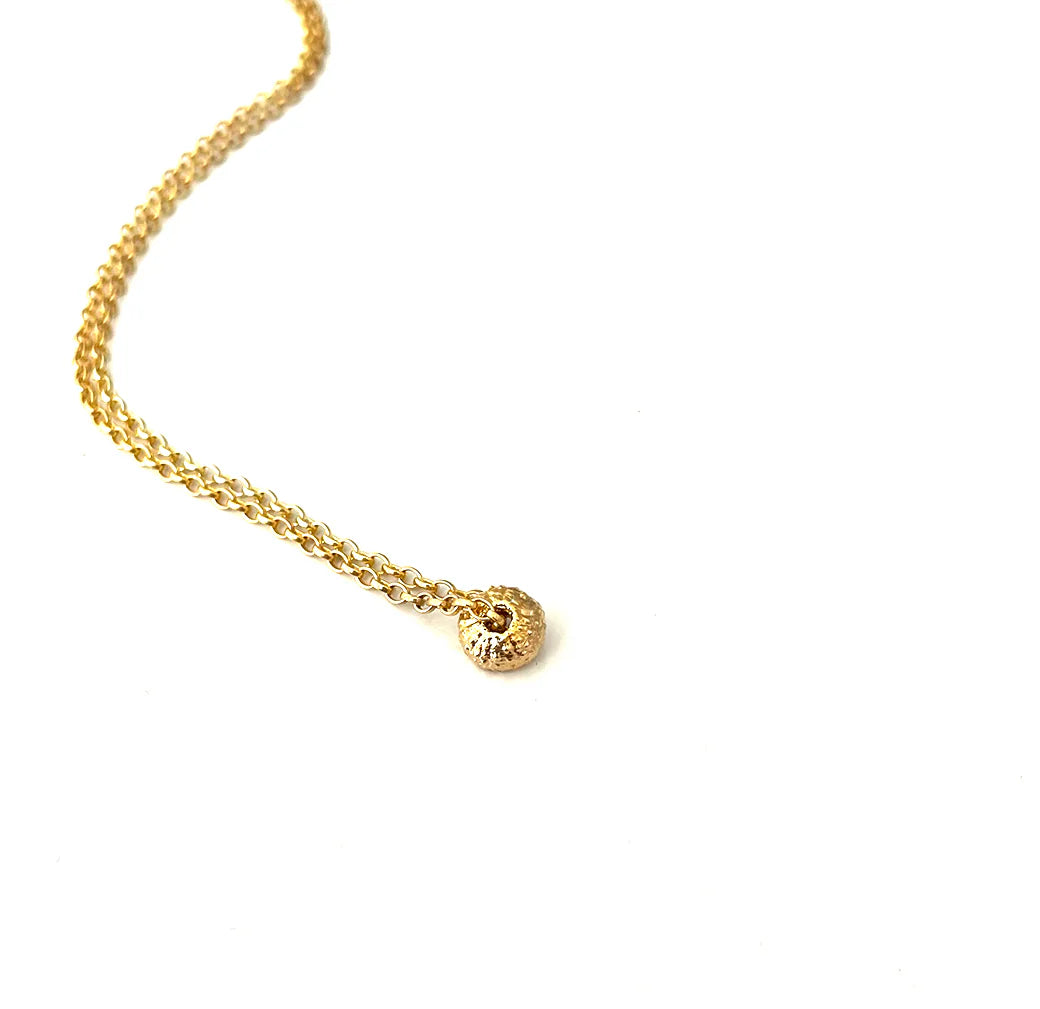 The Sea Urchin Necklace Tiny by Jennifer Kinnear features a small, textured, round gold-plated silver pendant on a delicate gold chain, shown on a plain white background. Available in silver or gold.