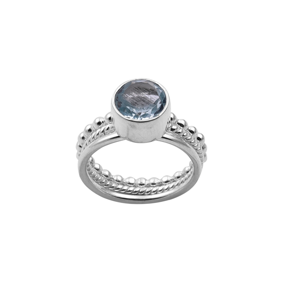 A handmade jewellery piece, the Watermelon Tropical Triple Stacking Blue Topaz Silver Ring features a round Blue Topaz gemstone in the center. The band has a unique design with small round beads along its sides and a twisted rope pattern encircling the middle, perfect for stacking sterling silver rings. The gemstone is set in a smooth bezel setting.