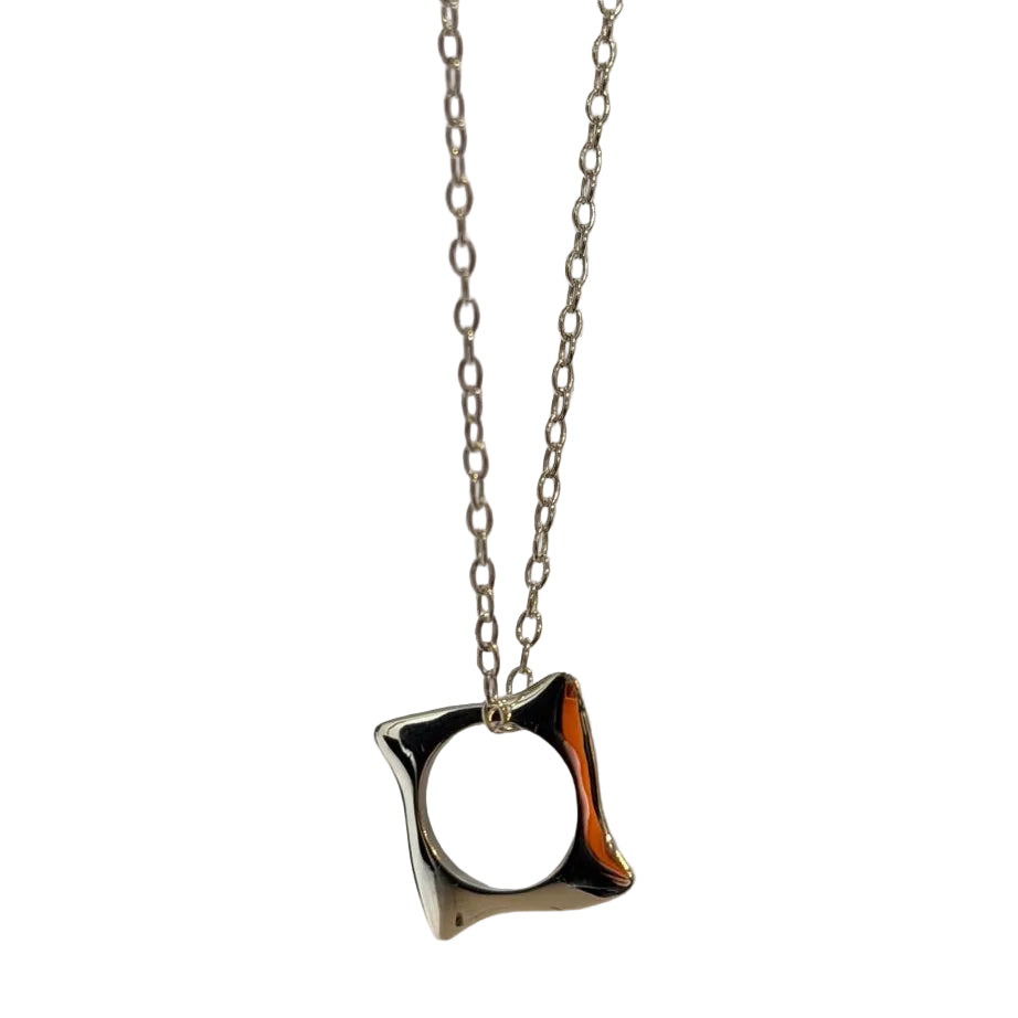 The Waves Necklace Silver by Andrea Mears Jewellery features a geometric, irregular square-shaped pendant with a central circular hole, crafted in silver on a delicate chain—ideal for everyday wear and showcased against a light background.