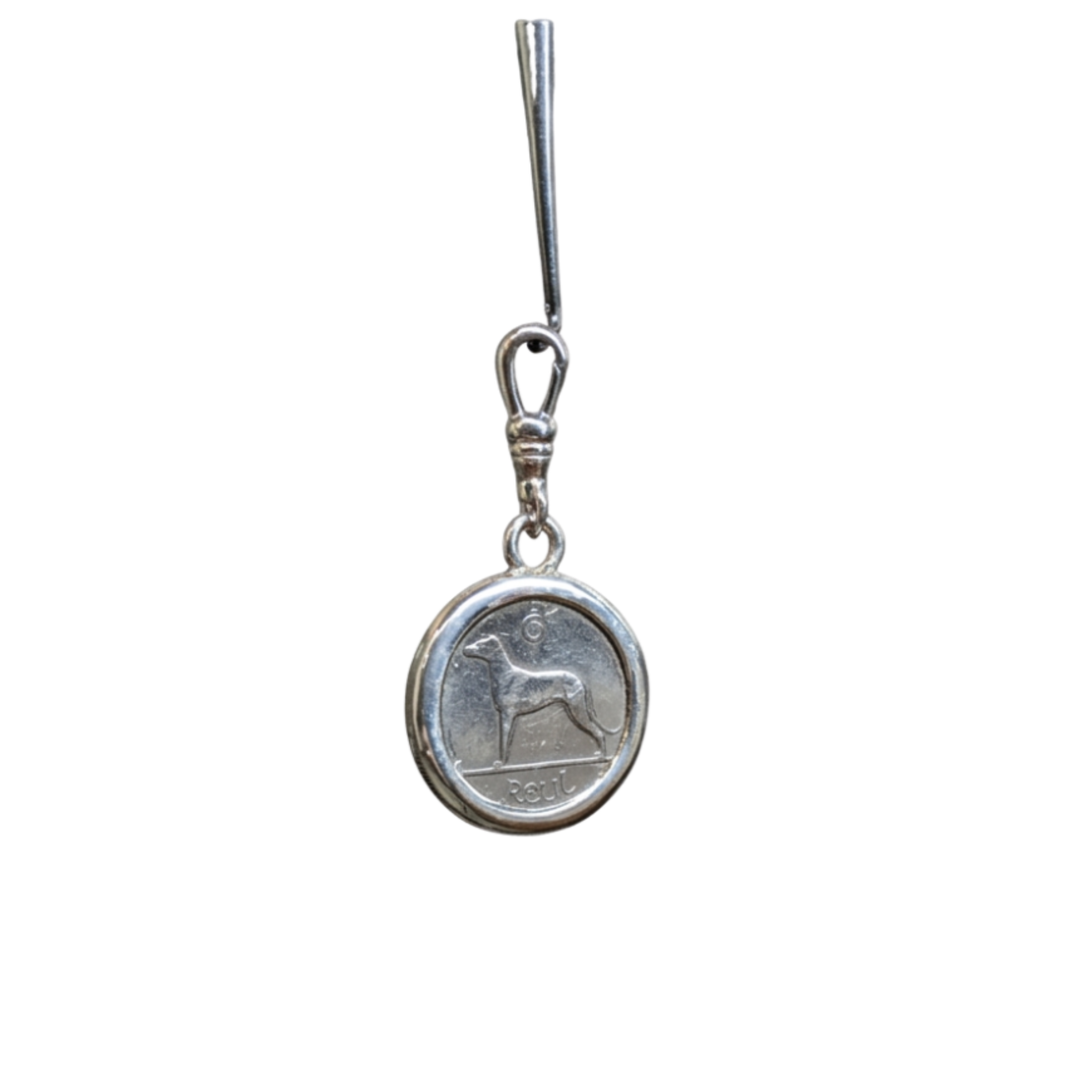 The Wolf Hound Silver Pendant by The Silver Rabbit is a handcrafted sterling silver piece featuring an Irish sixpence coin with a wolfhound design and "PESA" inscription, attached to a simple metallic hook.