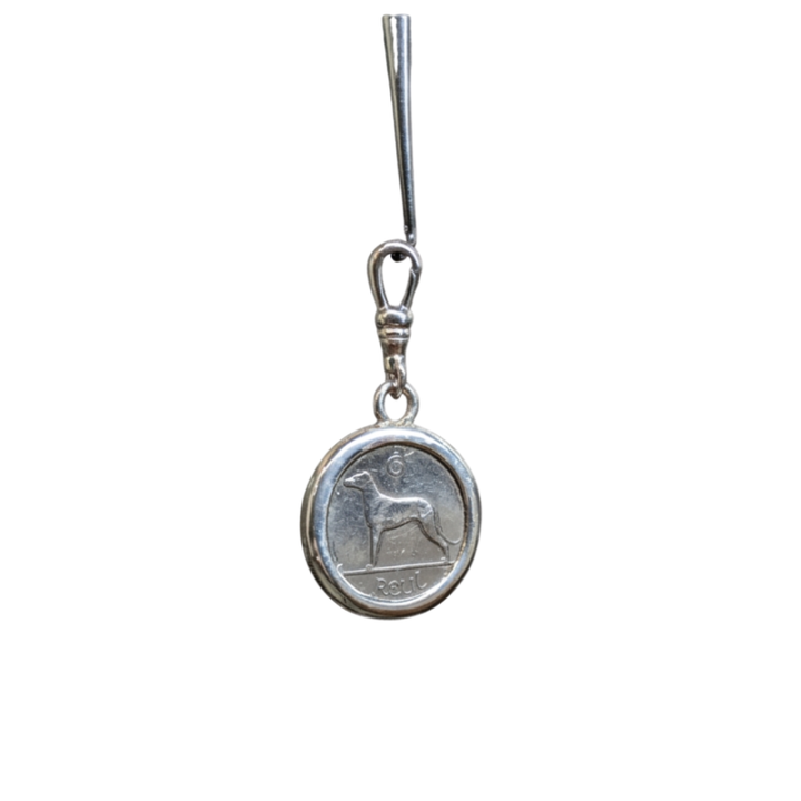 The Wolf Hound Silver Pendant by The Silver Rabbit is a handcrafted sterling silver piece featuring an Irish sixpence coin with a wolfhound design and "PESA" inscription, attached to a simple metallic hook.