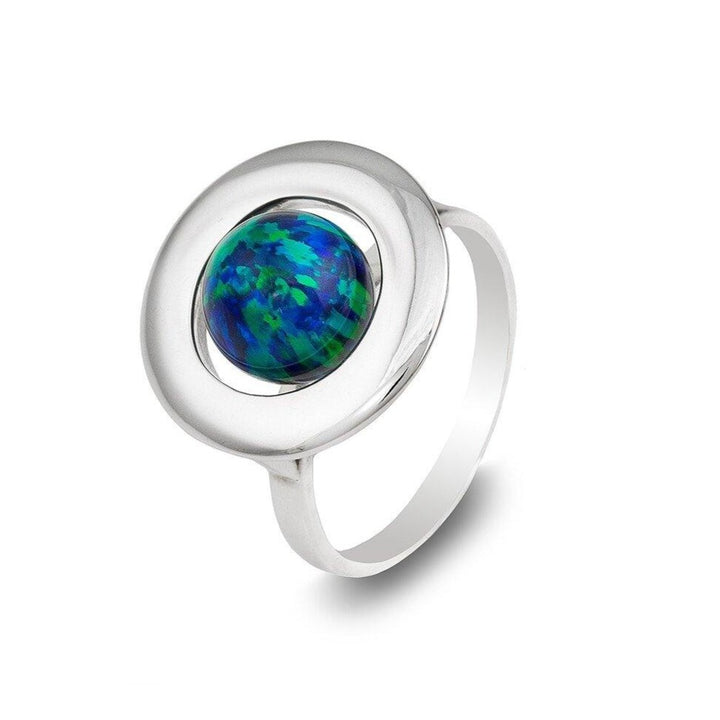 A sterling silver ring featuring a round, blue-green opal stone set in the center of a wide, circular bezel. The Home Planet Night Sky Opal by Cosmic Boulevard displays a vibrant mix of blue and green hues with flashes of darker tones, giving it an iridescent appearance. The ring band is smooth and polished.