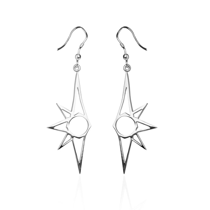 A pair of Starlight Earrings by Cosmic Boulevard with a unique, geometric starburst design, featuring a central circle and multiple pointed edges. The earrings are suspended from simple hooks. They are shown on a white background with a slight reflection, capturing the essence of starlight.