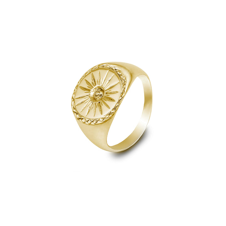 The Cosmic Boulevard Starburst 9ct Gold Signet Ring features an embossed sunburst design with a central engraved face. The band is smooth and polished, and the round face of this handmade signet ring has additional intricate detailing around the edge.